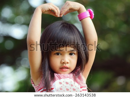 Portrait children, Sa Rang Hae Yo, Little asian girl doing heart shape in the park
