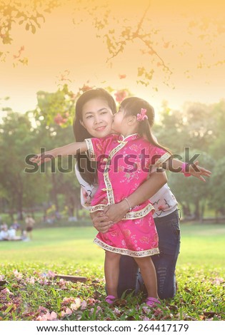 Asian family, Girls in cheongsam kissing her mather and laughing happily in park