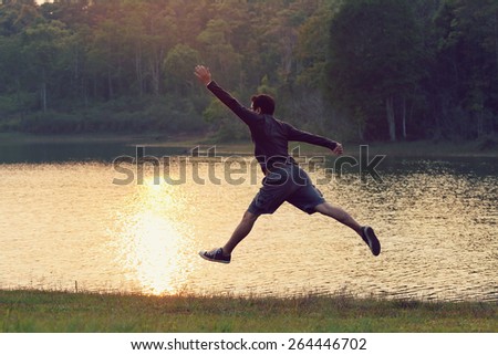 Jumps freedom, Asian man jumping on the river, during sunset, retro and vintage tone