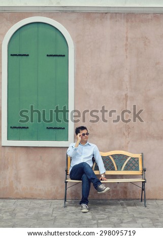Asian Lifestyle, Asian man wearing glasses sitting on a chair and green window.