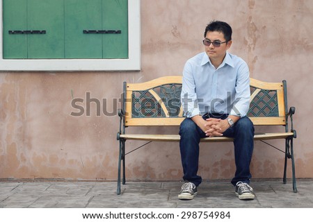 Asian Lifestyle, Asian man wearing glasses sitting on a chair and green window.