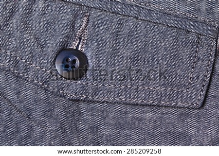 Black button pocket on gray color pants background.