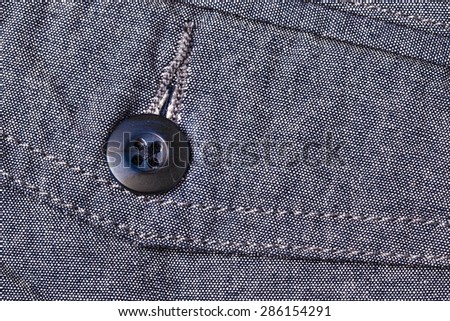 Black button pocket on gray color pants background.