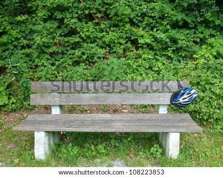 A cycle helmet hanging on a bench in the forest