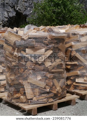 Wood for the fire place in plastic bags on wooden pallets along a road in the mountains of Switzerland