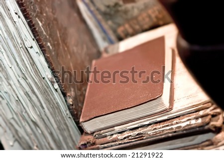 Old book with torn edges lying on the dusty shelf