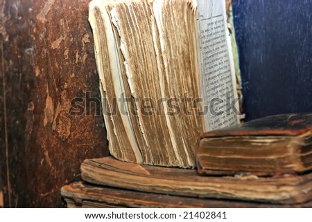 Old books with torn edges lying on the dusty shelf