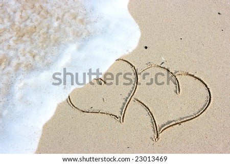 Two hearts drawing on the sandy beach