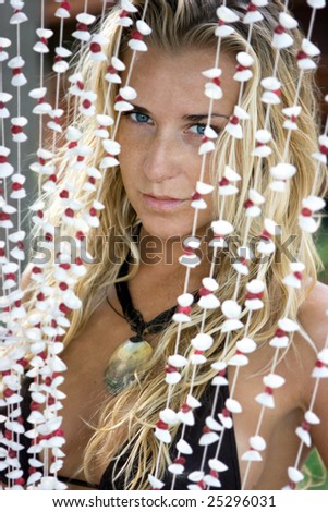 Beautiful blonde girl looking through the shell curtains