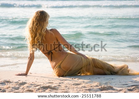 Blonde mermaid lying on the beach and turned her back