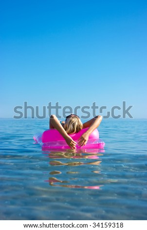 Beautiful blonde girl floating on inflatable raft in the sea