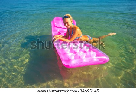 Pretty blonde girl floating on inflatable raft