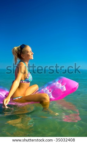 Pretty blonde girl floating on inflatable raft