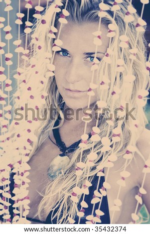 Beautiful blonde girl looking through the shell curtains on vintage photo