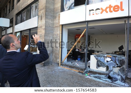 RIO DE JANEIRO, BRAZIL - OCTOBER 08: A local resident take pictures of a destroyed Nextel store at Rio de janeiro\'s downtown on the day after schoolteachers demonstrations demanding better wages on October 8th, 2013 in Rio de Janeiro, Brazil.