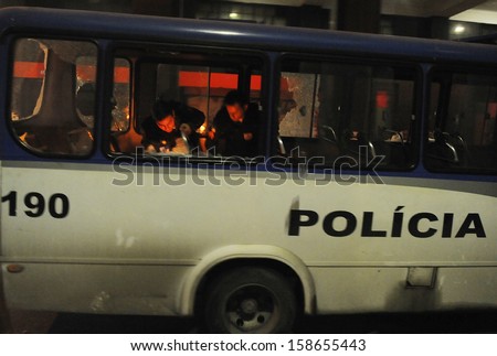 RIO DE JANEIRO, BRAZIL - OCTOBER 15: Anti-Riot police officer attempt to control a fire set inside a police bus along the city center main avenue, Rio Branco, during a protest in support to the teacher\'s strike as the annual October 15 Teachers\' Day holid