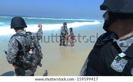 RIO DE JANEIRO, BRAZIL - 21 OCTOBER 2013: A member of the National Force Security Battalion removes children from the security perimeter at the Barra da Tijuca.