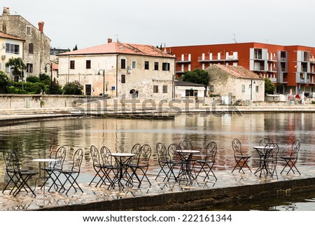 Typical istrian architecture: sea, walls, houses, windows, stones and streets of Porec in Croatia. Chairs and table on the sea