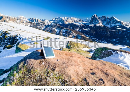 Tablet PC and pen on the Dolomites with rock, snow-capped peaks and conifers