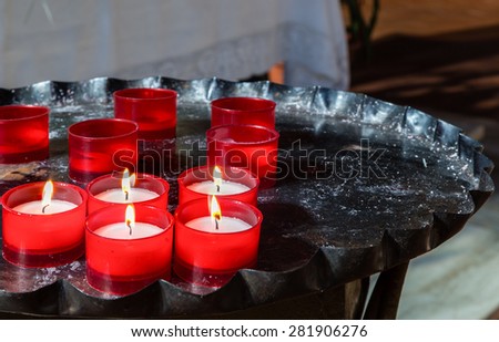 red votive candles arranged on old black iron candlestick, some still burning