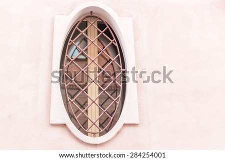 Iron grating round window with beige wooden frame