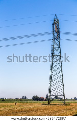 agriculture and industry - woman dressed in pink while collecting agricultural products under a high voltage giant pylon