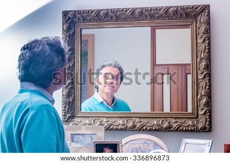 handsome middle-aged man looking in the mirror with nice look