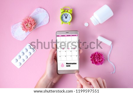 Tampon, feminine, sanitary pads for critical days, feminine calendar, alarm clock, pain pills during menstruation and a pink flower on a pink background. Care of hygiene during menstruation.
