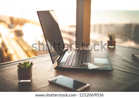 Cozy workplace in home office with laptop on table against the windows at sunset for online business, working, study. Remote work and earning online