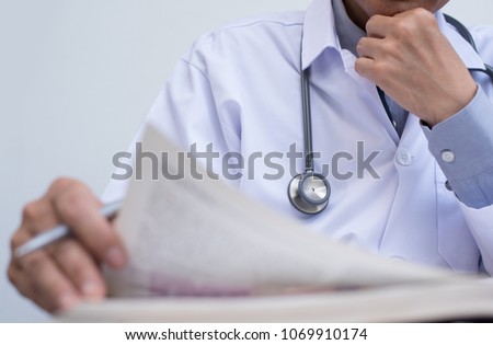 Doctor or medical student concentrate reading  anatomy textbook for medical research, close up. Selective focus on stethoscope with copy space.
