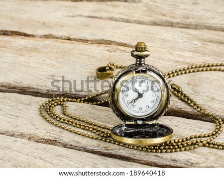 Ancient pocket watch and necklace isolated on old wooden  background.