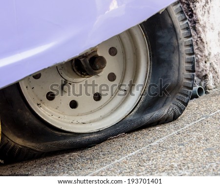 Leaked tire of purple old small car.
