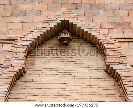 High brick wall and wooden ancient lamp with brick frame above the doorway of ancient style house.