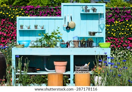 Outdoor kitchen, Kitchenware on blue wooden wall, kitchen in the flowers garden.