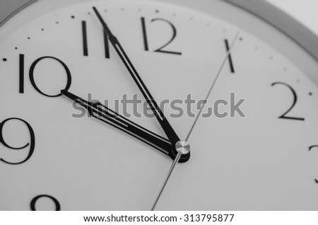 Close up on wall clock, office clock selective focus at needles  center in black and white.