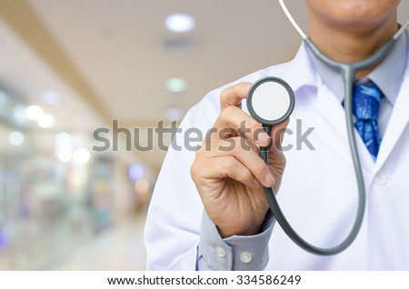 Medical doctor holding stethoscope with blurred hospital  background.