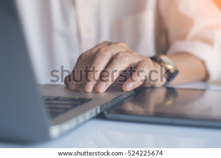 Close up of businessman working on laptop computer and tablet pc and rest his hand on keyboard with reflection, online working internet of things IOT, warm tone.