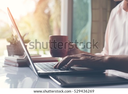 Business man working on laptop computer and drinking coffee in late afternoon, close up, vintage style.