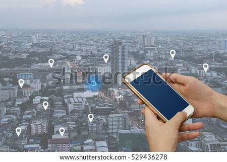 Woman hand using mobile smartphone searching location on map and pin above blue tone city scape and network connection, internet of things, satellite navigation system app, smart journey concept