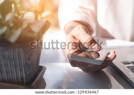 Businessman working on laptop computer and mobile smartphone with screen reflection, digital data transference online working, IOT internet of things concept, warm tone.
