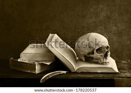 still life art photography on human skull  with open book on desk