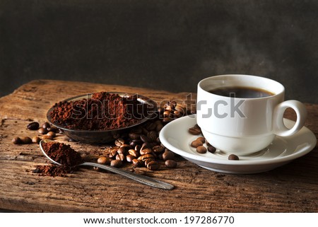 Hot Coffee in  cup and coffee beans,ground coffee on a wooden table.