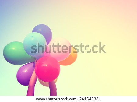 Girl hand holding colorful balloons done with a retro vintage instagram filter effect, concept of happy birth day in summer and wedding honeymoon party (Vintage color tone)