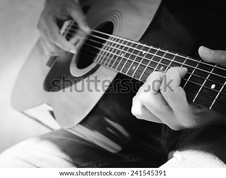 Details of performer man hands playing acoustic guitar musical, black and white photo- B&W
