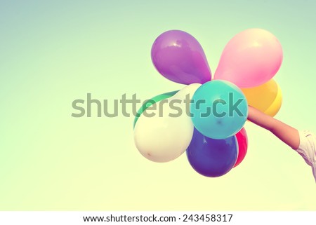 Girl hand holding multi colored balloons done with a retro vintage instagram filter effect, concept of happy birth day in summer and wedding honeymoon party (Vintage color tone)