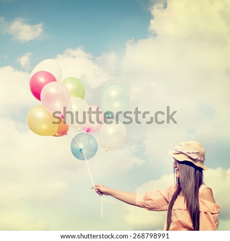 Vintage photo of  Happy young red hair woman  holding colorful balloons and flying on clouds sky background.