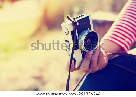Vintage young hipster girl photographer hand holding retro camera, soft focus