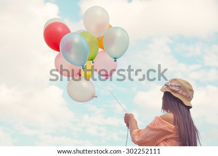 Vintage pastel color of Happy young red hair Ethnicities Asian women holding colorful balloons and flying on clouds sky background