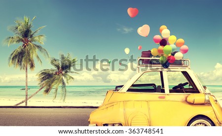 Vintage yellow car with heart colorful balloon on beach blue sky - concept of love in summer and wedding. Honeymoon trip