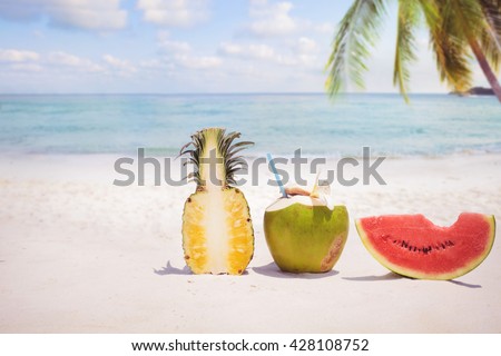 Summer fruit concept with coconut cocktial, watermelon and pineapple on sandy tropical beach